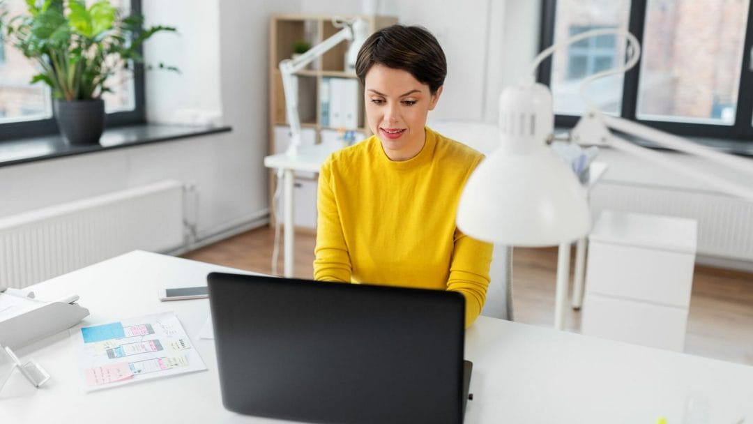 A woman in yellow using a laptop